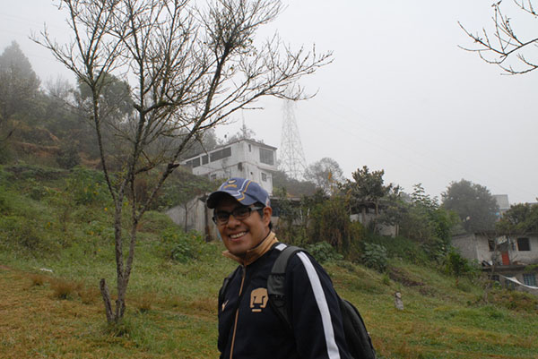 Photograph of a smiling man with houses on a hillside in the background.