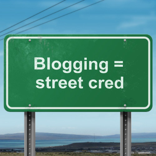 Image of a green street sign that says "Blogging = street cred".