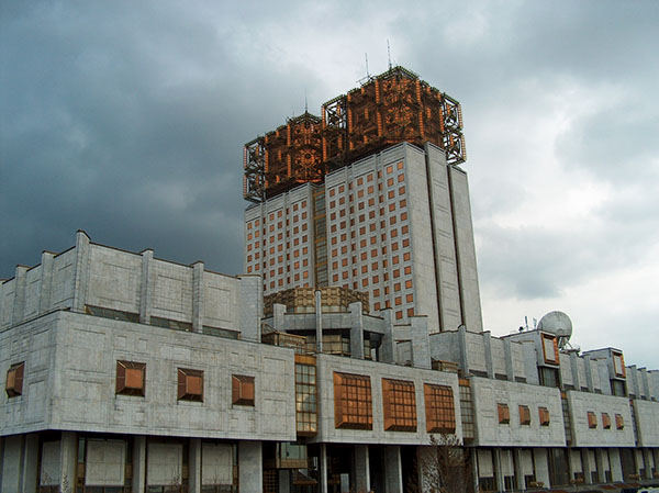 Photograph of a grey building with orange-colored features.