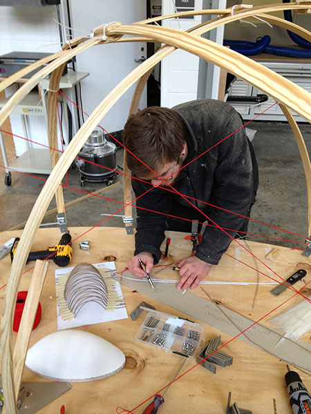 An architecture student amidst various forms of design media in the studio.