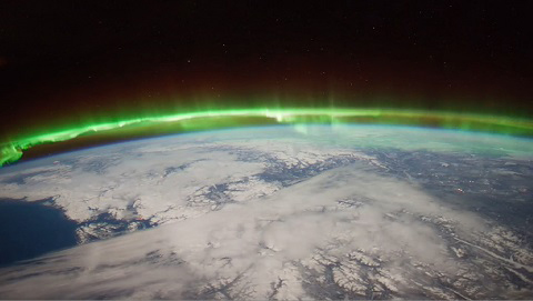 Image of aurora lights at the edge of the curve of the earth from space.