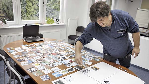 A man leaning over a table filled with images.