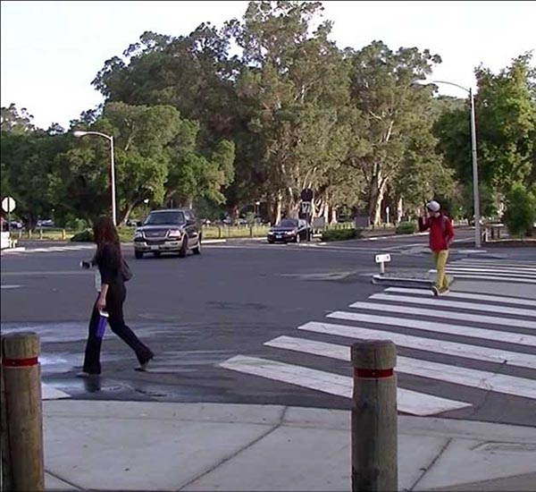 Photograph of two people walking across a crosswalk looking to the side at traffic.