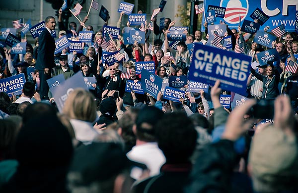 Barack Obama walking through a crowd of people holding up campaign signs.