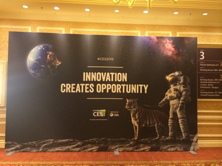 Poster at a conference reading: INNOVATION CREATES OPPORTUNITY, over pictures of the earth from outer space, a nebula, an astronaut standing on the moon, and a tiger next to them.