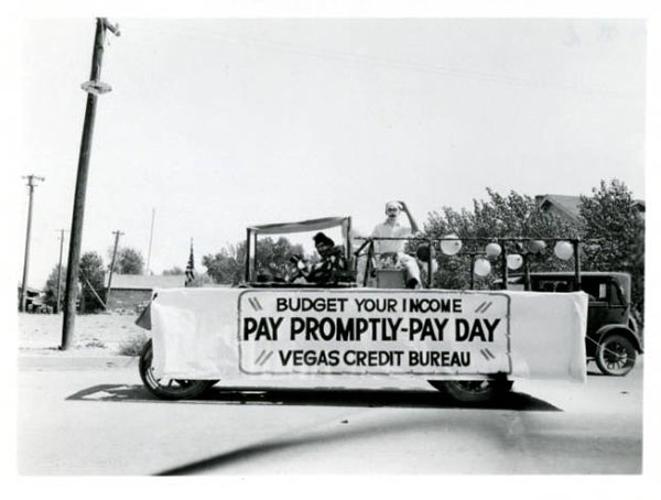 A parade vehicle with a banner that reads "Budget your income. Pay promptly-pay day. Vegas Credit Bureau."