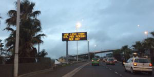 Photograph of a highway with a sign above it reading "Use less than 87L per person per day."