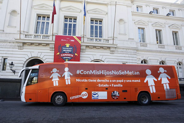 Un bus anaranjado con figuras de niña, niño, hombre y mejur que dice #ConMisHijosSeMetan y Nicolás tiene derecho a un papá y una mamá.