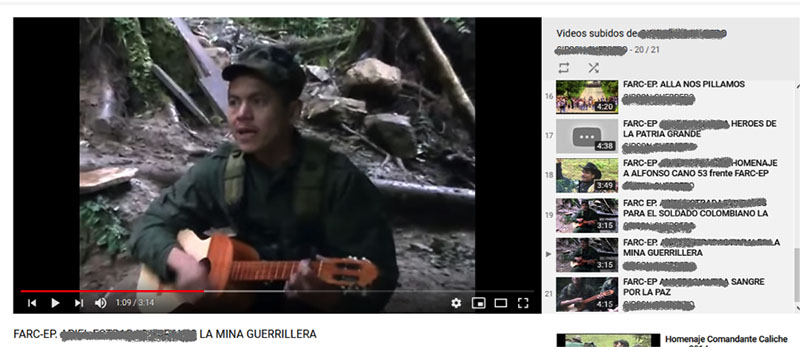 A screen capture of a FARC YouTube channel. The still shows a man dressed in green fatigues playing an acoustic guitar.