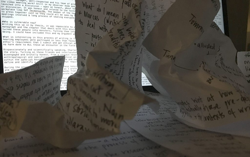 The image shows crumpled paper in the foreground and a computer screen with a text file open in the background. The paper in the foreground is scribbled full of notes - the discarded drafts of earlier versions of the article I was struggling to write. The text on the computer screen is of the umpteenth draft of the same article - no easier to write on a computer than it was with pen and paper.