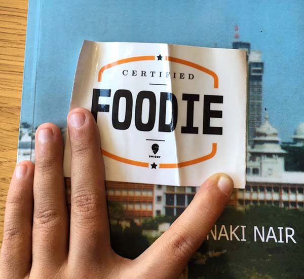A hand opens open a curled sticker reading "Certified foodie"