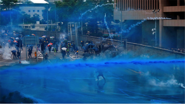 Police officers spray blue-dyed water on protestors.