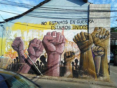 A street mural shows fists rising from the ground, and a caption reading "we're not at war, we're united."