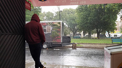 A man stands under an awning and watches the rain.