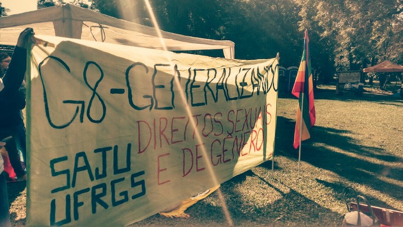 At a sunny park, a large banner is held that says "G-8 Generalizando" and "sex and gender rights." A rainbow pride flag stands on a pole next to the banner.