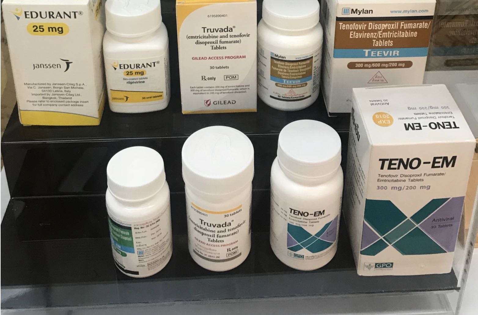 A shelf containing different brands of HIV prophylactic treatments in a Bangkok clinic. Thai GPO Teno-Em is featured in the lower right-hand corner. Photo credit: author