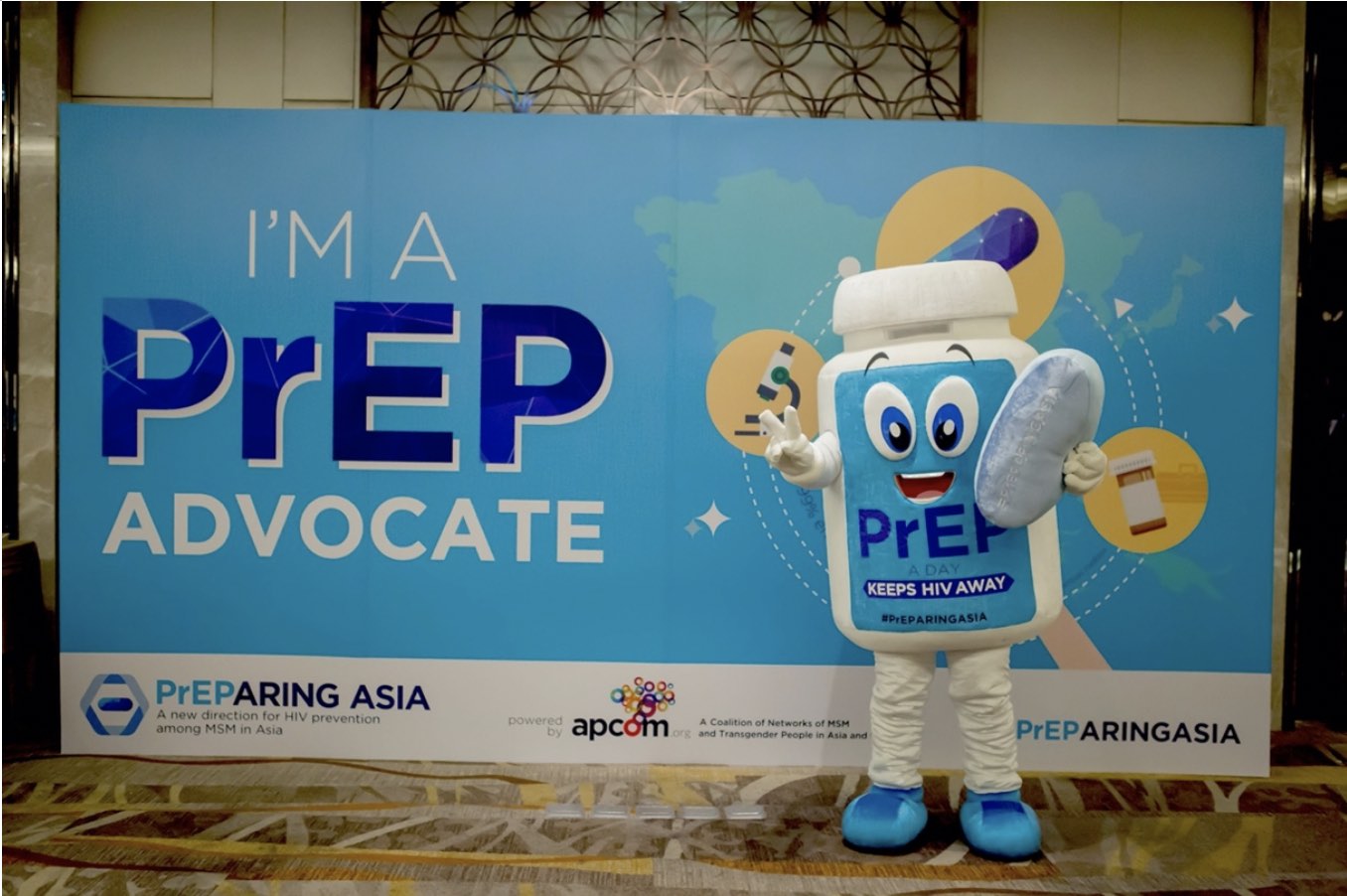 A picture of a cartoonish PrEP mascot, with text reading “PrEP a day keeps HIV away. The photo is from a conference titled “PrEParing Asia: A new direction for HIV prevention among MSM in Asia. Photo credit: APCOM Foundation – Asia-Pacific Coalition on Male Sexual Health.