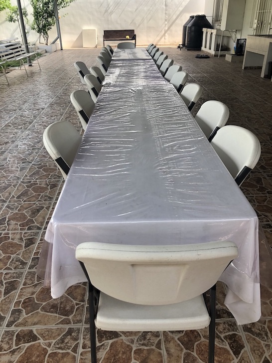 A long, clean empty plastic table with chairs tucked in