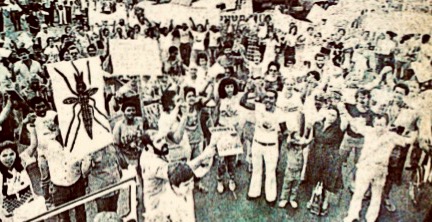 Black and white photo of protestors, some are holding signs and, most notably, one of them has a mosquito image. 
