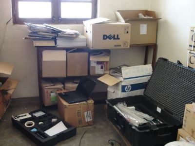 Laptop and other equipment for TLC testing amongst a bookshelf with loose cardboard boxes