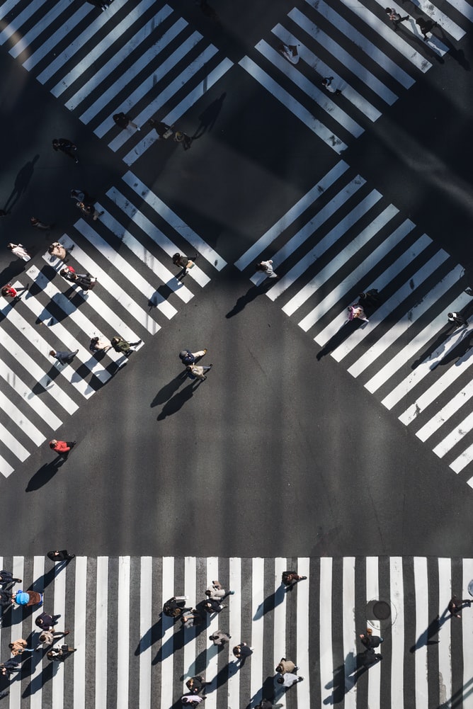 Aerial image of crossroads whereby people cross the street using three zebra crossings.Two are crossed between each other, the third zebra crossing is horizontal, located under the crossed two zebra crossings.