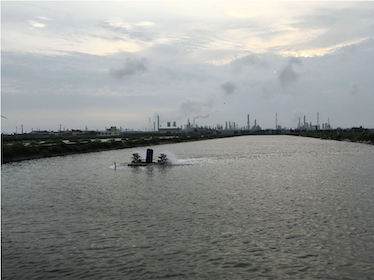 A large fishfarm in front of a horizon of smoke stacks with smoke from the Naphtha Sixth Cracking Plant in Mailiao