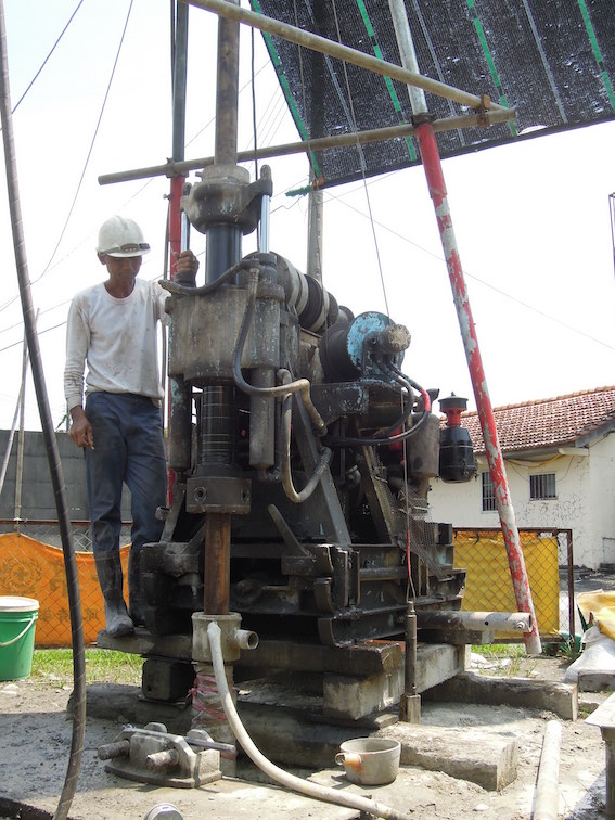 A man operates a drill that is being used to "core" and collect "core" samples.