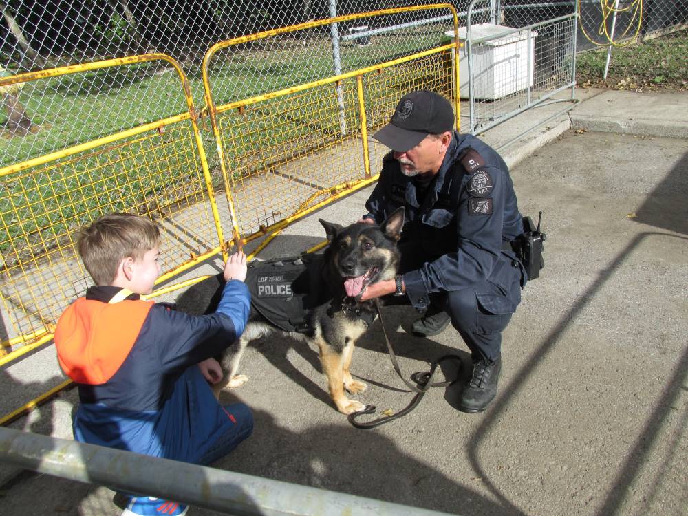 A young boy tenderly pets a police dog, who is held about the shoulder by a member of the Toronto Police Force
