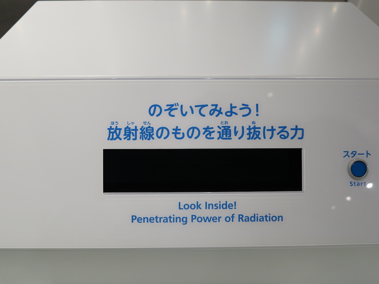A large white metal piece of equipment with a small black window says, "Look inside! Penetrating Power of Radiation." A start button is to the left of the window and text.