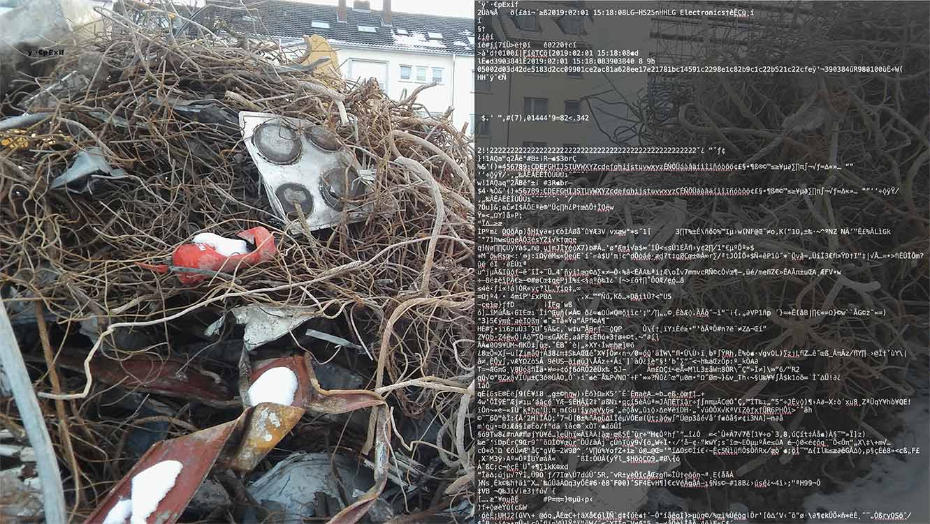 There is a large pile of trash here which has been overgrown by too many vines. It is winter and the vines are thick and brown while snow covers what seems to be a stove top and a red buoy. This is the left side. On the right there is a string of white computer text which covers that side of the photo in a black transparent box. 