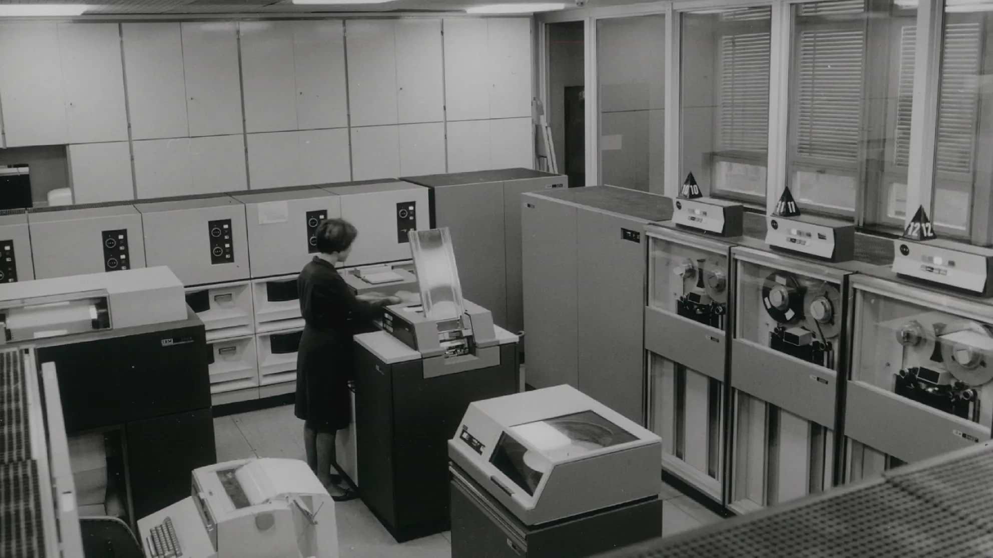 Woman manipulating an IBM mainframe computer, image in black and white. 