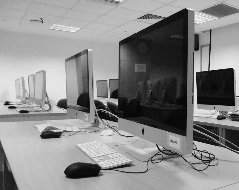 Grayscale image of iMac computers in what appears to be an office or computer lab.