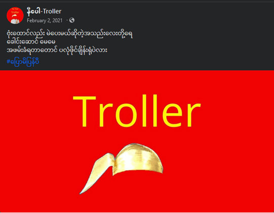 ပုံစာ (၂) - “နီပေါ Troller” ဟုအမည်ရသော Facebook စာမျက်နှာမှ အောင်ဆန်းစုကြည်နှင့် NLD ပါတီကိုထောက်ခံကြသူများအား လှောင်ပြောင်သောပို့စ်တစ်ခုကိုတင်ခဲ့သည်။ ပုံတွင် မြန်မာအမျိုးသားများ ပွဲလမ်းသဘင်နှင့်အရေးကြီးသောအခမ်းအနားများတွင်ဝတ်ဆင်လေ့ရှိသော၊ အထူးသဖြင့် နိုင်ငံရေးနှင့်ပတ်သတ်သောပွဲလမ်းသဘင်အခင်းအကျင်းများတွင် နိုင်ငံရေးသမားအမျိုးသားများဝတ်ဆင်လေ့ရှိသော မြန်မာ့ရိုးရာခေါင်းပေါင်းတစ်ခုပါဝင်သည်။ ပုံအပေါ်မှစာသားသည် “Troller” ဟုရေးသားထားပြီး ပုံနောက်ခံအရောင်ကို NLD ပါတီ၏သင်္ကေတအရောင်အနီရောင်ခြယ်ထားသည်။ (ဤပုံကို စက်တင်ဘာလ ၂၇ ရက်နေ့၊ ၂၀၂၃ ခုနှစ်တွင်ရယူခဲ့သည်။) 