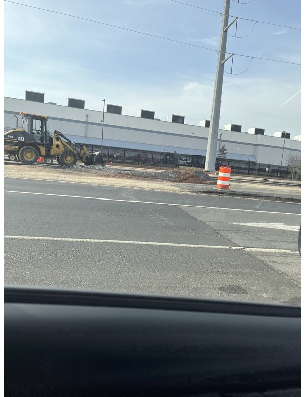 A tractor sits in front of a warehouse.