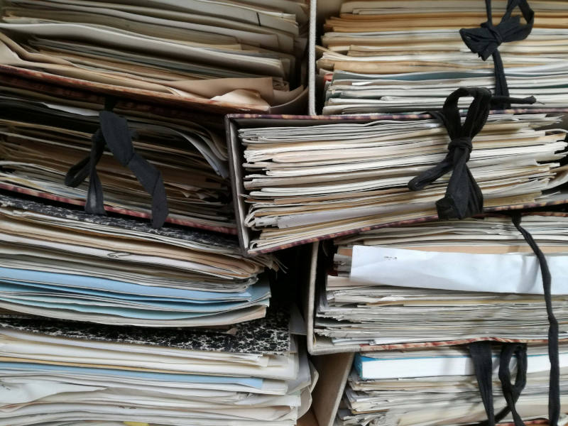 A stack of binders with assorted papers.