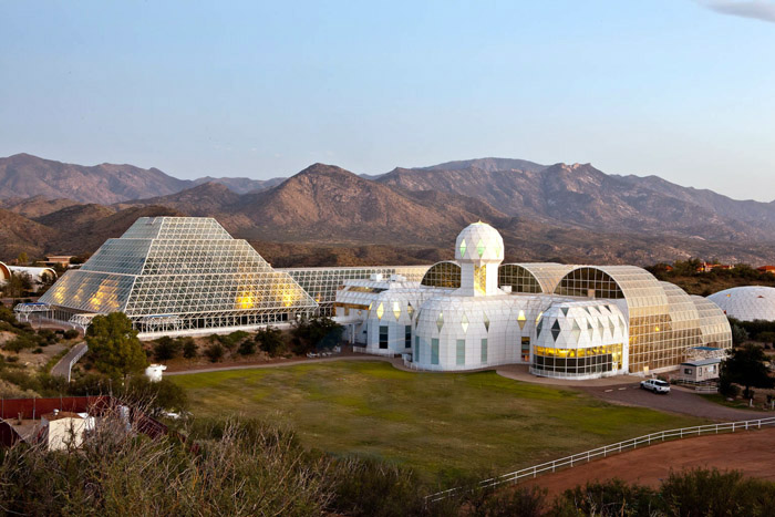 A laboratory with strange white and glass buildings in front of desert mountains in the dusk.
