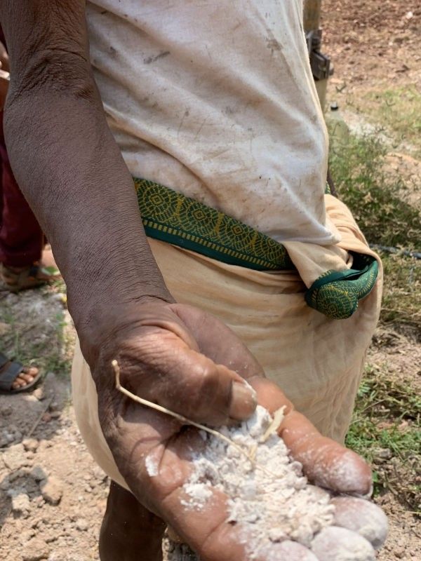 A picture of the hand of a farmer with his palm facing towards the camera. There is white powder-like substances which are abraded soil and rocks in the farmer. 