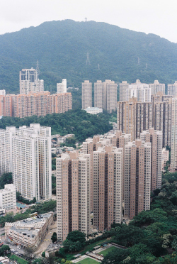 Dense high-rise apartment buildings in Hong Kong surrounded by green hills, representing typical urban residential housing where ash-storage units may be hidden among living spaces