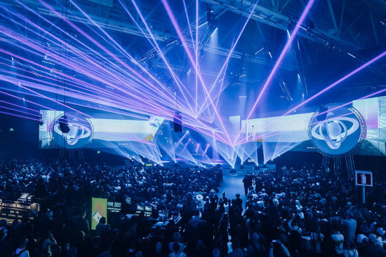 A conference stage surrounded by a crowd of people and dramatic stage lighting.