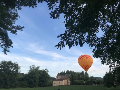 A french chateau in the countryside with a hot air balloon rising over it 