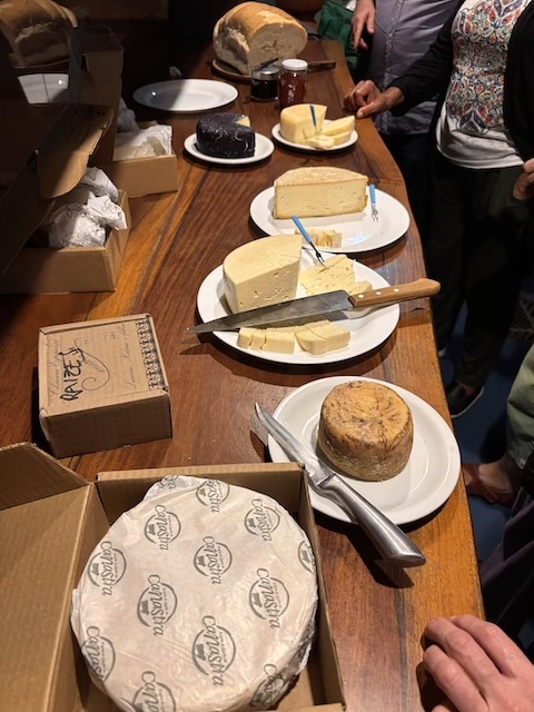 A wooden table with different kinds of cheese cut and displayed.