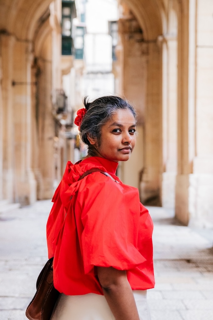 The author Tanu Biswas looks back while walking through a corridor on an academic institution.
