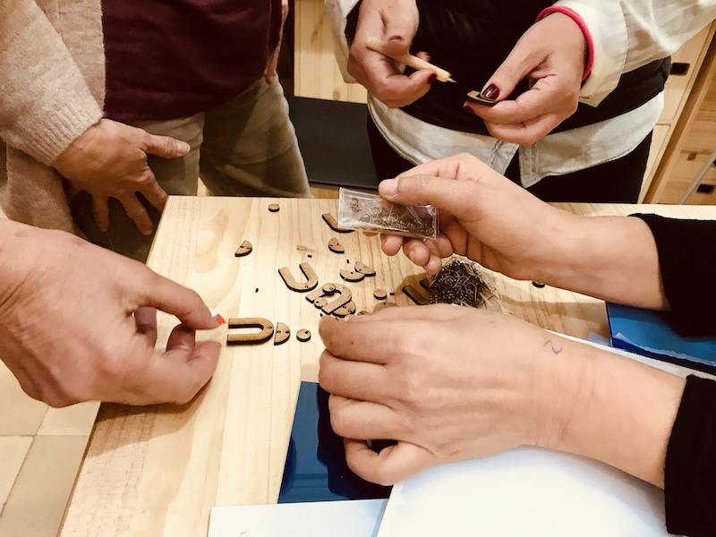 A close caption of 6 hands at a maker space, handling laser-cut artifacts.