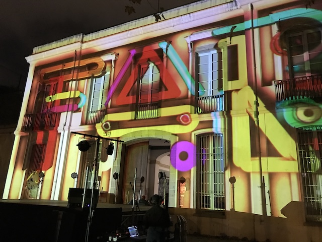 An old building with colorful lights projected on its façade.