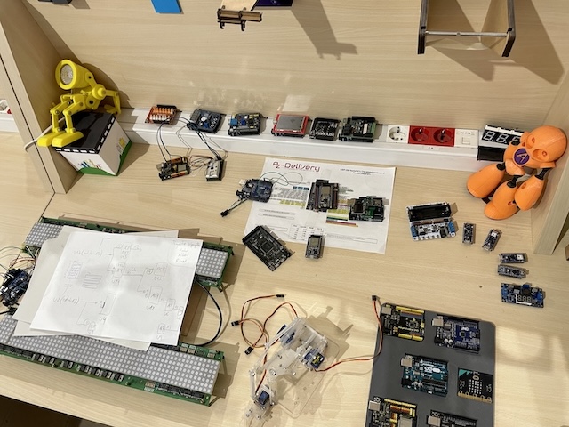 A wooden table with different robotic and electronic pieces.