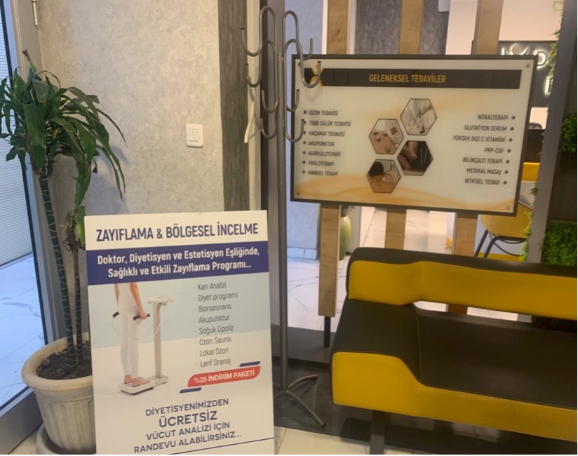 Posters in a hospital waiting area advertise a weight-loss and aesthetic program alongside traditional treatments, displayed side by side on a wall.