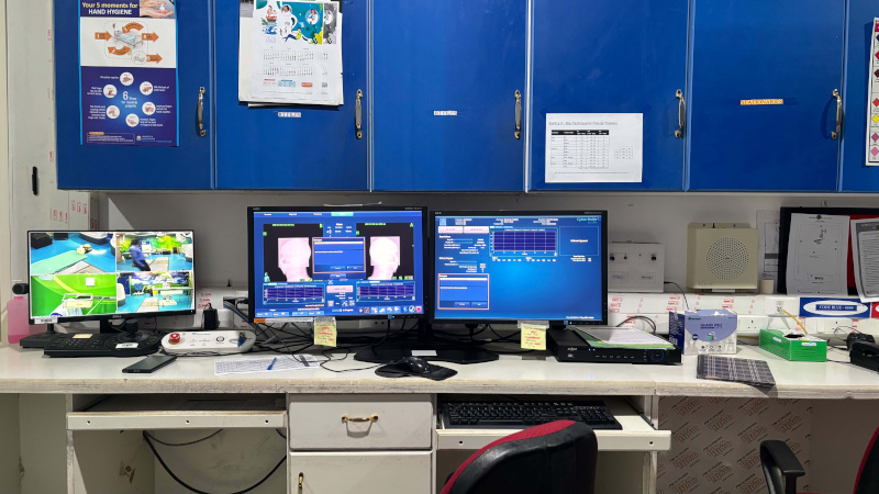 Control room for the CyberKnife radiation therapy system, with multiple computer monitors displaying treatment imaging, system controls, and live camera feeds.