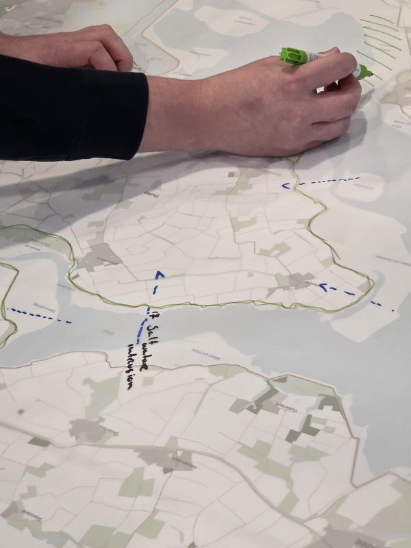 A close up of a map of the Netherlands, with a hand in the top third of the image drawing arrows on the map.
