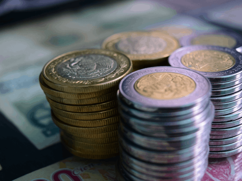 Close-up of stacked gold and silver coins on various currency notes, symbolizing wealth and savings.