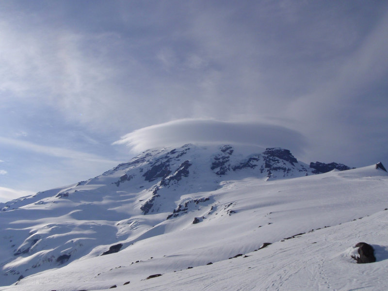 This image shows a lenticular cloud that has formed around the peak of a mountain, as moving air rises up it and cools at the same altitude.